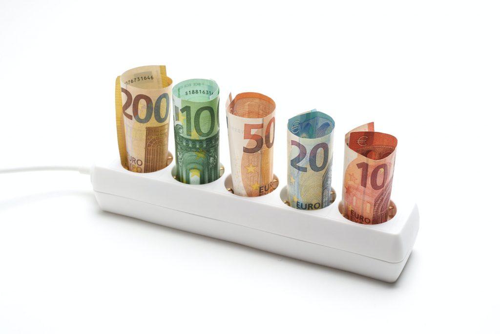 Electric plug strip with banknotes on white background, concept spending electrical energy